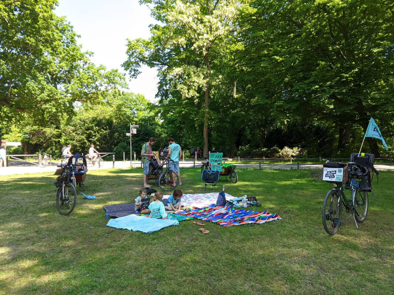 Eltern und Kinder mit Klimalisten-Shirts sitzen im Park.