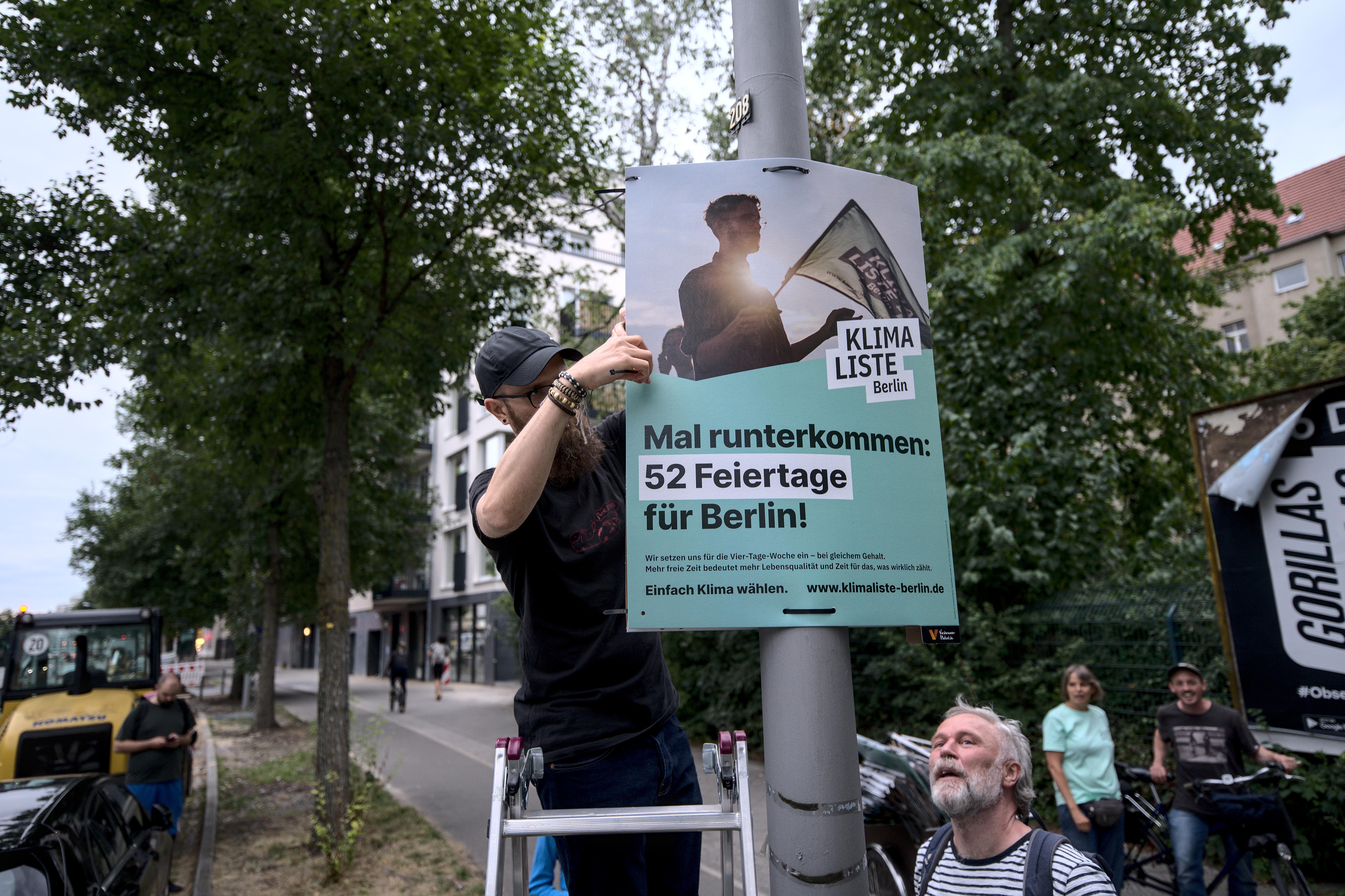 Aktivist:innen der Klimaliste Berlin hängen ein Wahlplakat auf